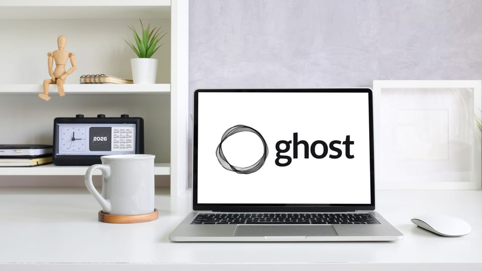 Ghost CMS logo displayed on laptop in modern workspace setup