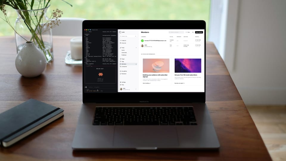 MacBook Pro on a wooden desk showing a terminal with ghst CLI commands alongside the Ghost admin Members panel, with a notebook and plant in the background